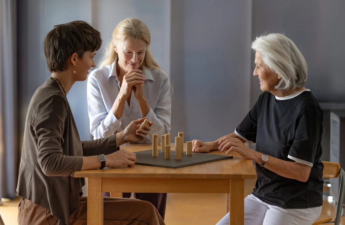 Drei Frauen im Gespräch an einem Tisch mit Aufstellungsfiguren